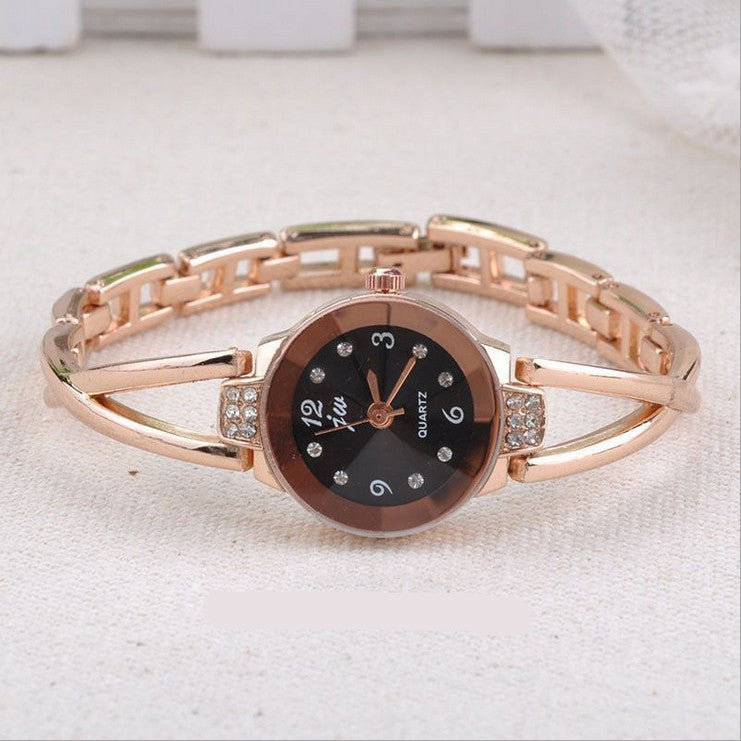 Rose gold bracelet watch with black dial on a light fabric background