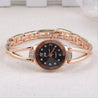 Rose gold bracelet watch with black dial on a light fabric background
